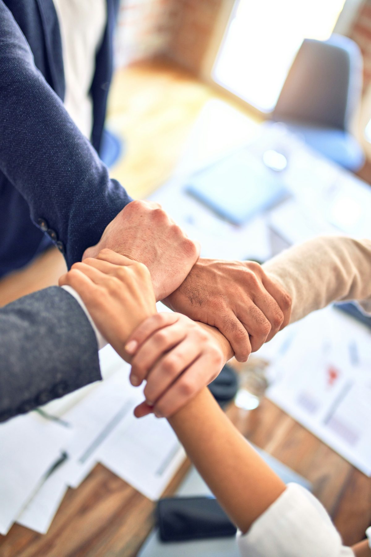 Team members joining hands over a work table