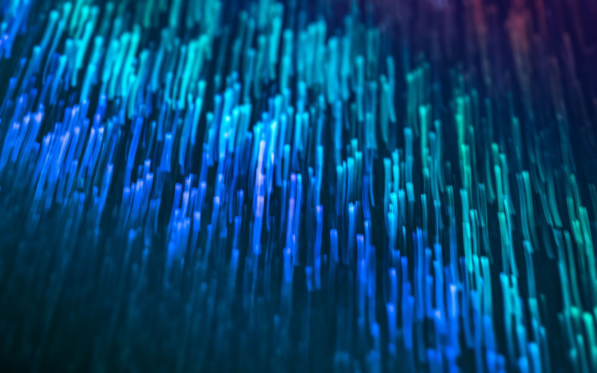 Streaks of blue and teal fibre-optic light falling through darkness